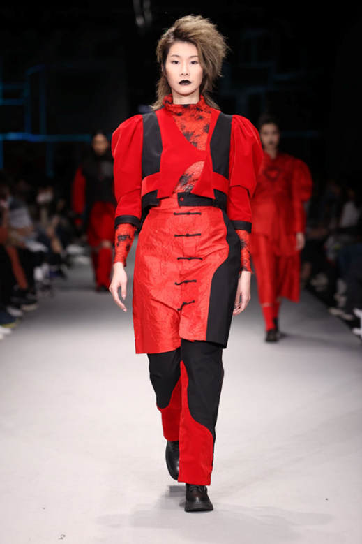 文化部李連權次長頒發最佳展演學校獎。  內容： 2022年臺北時裝週在文化部主辦下魅力登場，為鼓勵學校培育人才並用心參與臺北時裝週，此次的校際展演特別評選出表現最好的學校，實踐大學服裝設計學系、服飾設計與經營學系以及時尚設計學系共同策劃，以「智能無界未來UNBOUNDED FUTURES」為命題，「跨界」結合數位影像創作與服裝造型設計，製作兼容三系教學特色。指涉在廣大的群體之下，每一位參演學生設計師皆為獨立存在的單元個體，風格迥異多元，各自針對所謂「服裝」的想像與解讀、探索自我的理想解答，並在2022年3月26日於臺北松山文創園區完整呈現，獲各界肯定，且由臺北時裝週所組成的專業評審團，評選為「最佳展演學校」。 在學生作品表現方面，除了實踐大學高雄校區服飾設計與經營學系饒文濤、張喬盈作品獲得網路票選人氣潛力設計新秀之外，來自於成立僅15年的時尚設計學系參演學生蔡又軒，從電腦的command鍵為靈感，以「Command loop」為題，將鍵盤擬人化成軍隊構想而成，故在服裝色澤上選用較為低調的墨綠、灰色、黑色，胸口的鏤空花形設計，與包款配件Logo相互輝映配搭，使該系列兼具優雅、實穿與設計感，得到多家媒體的關注與報導，並獲得本季臺北時裝週評審團的青睞，盛讚為極具商業潛能的作品，在參展的四所服裝與時尚相關校系，共計201套的作品中脫穎而出，獲選「潛力設計新秀」。